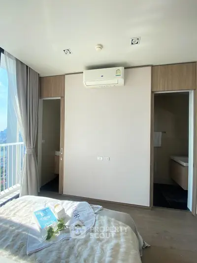 Modern bedroom with balcony view and air conditioning, featuring elegant decor and natural light.