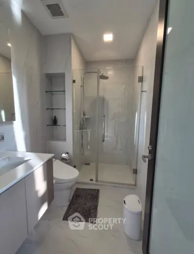 Modern bathroom with glass shower and sleek fixtures in luxury apartment.
