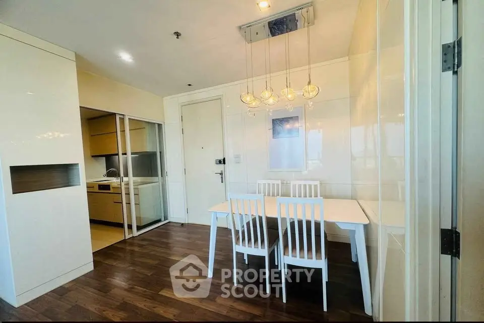 Modern dining area with sleek kitchen and elegant lighting in a stylish apartment.