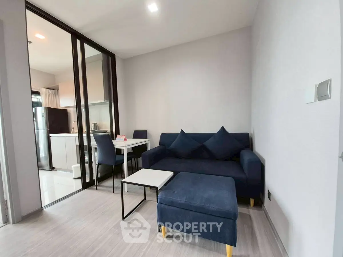 Modern living room with blue sofa and open kitchen layout in stylish apartment