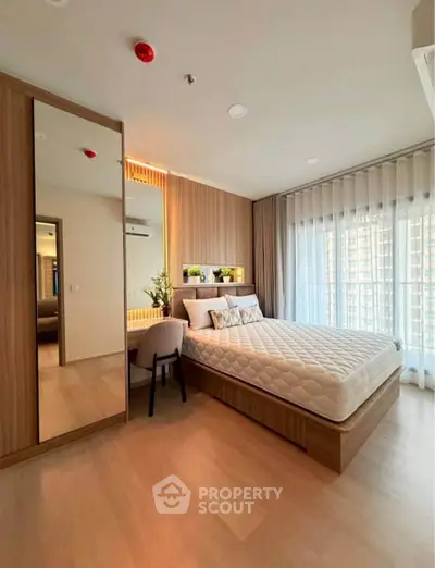 Modern bedroom with large window, wooden flooring, and stylish decor in a contemporary apartment.