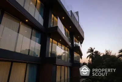 Modern apartment building with glass balconies and evening lighting