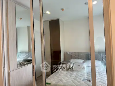Modern bedroom with mirrored wardrobe and cozy bedding in a stylish apartment.