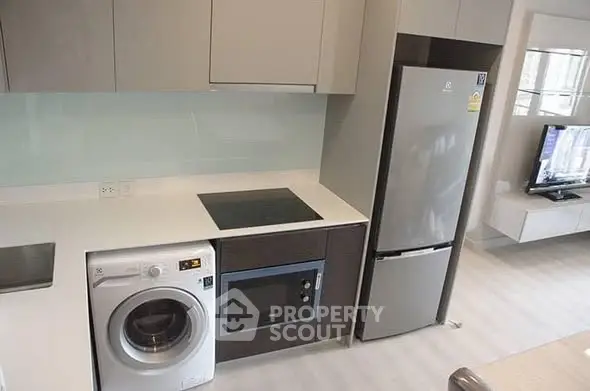 Modern kitchen with sleek appliances including washing machine and fridge