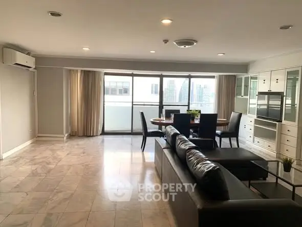 Spacious modern living room with large windows and city view, featuring sleek furniture and elegant decor.