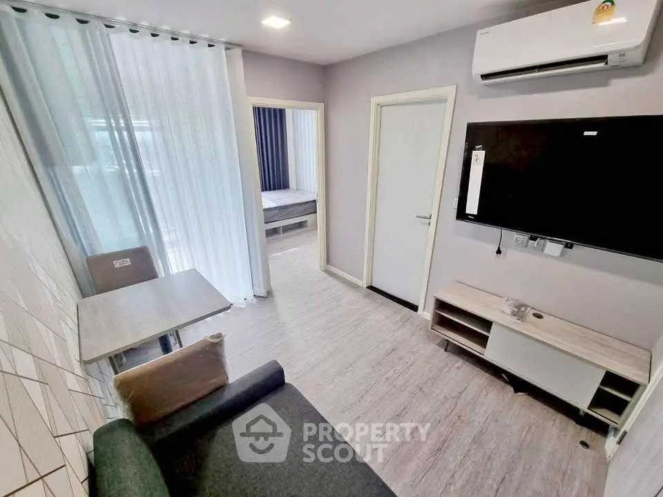 Modern living room with sleek furniture and wall-mounted TV in a cozy apartment.