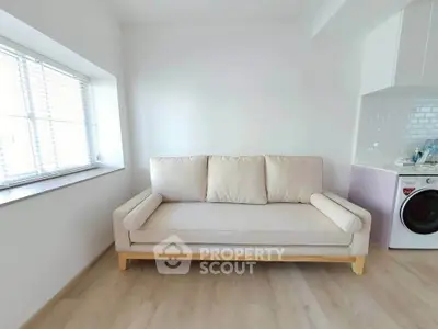 Bright living room with cozy beige sofa and washing machine in modern apartment.