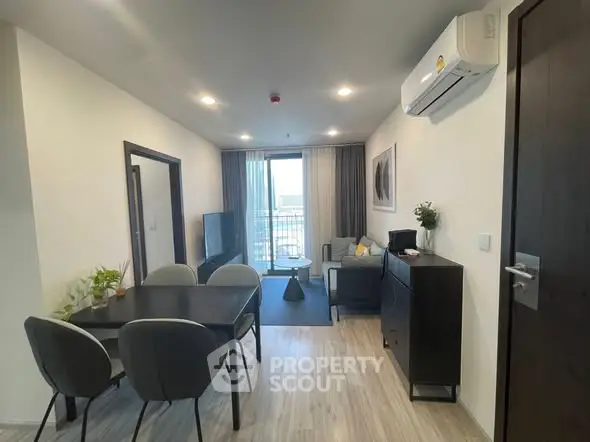 Modern living room with dining area and city view, featuring sleek furniture and air conditioning.
