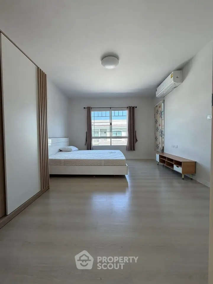 Spacious bedroom with modern furnishings and large window for natural light.