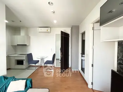 Modern apartment interior with open kitchen and cozy dining area, featuring sleek furniture and wooden flooring.