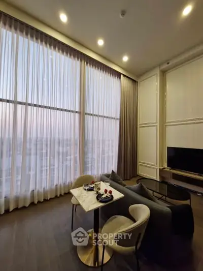 Luxurious high-ceiling living room with elegant decor and large windows offering stunning city views.