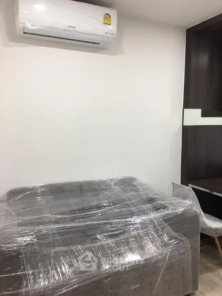 Modern living room with air conditioning and wrapped furniture, ready for move-in.