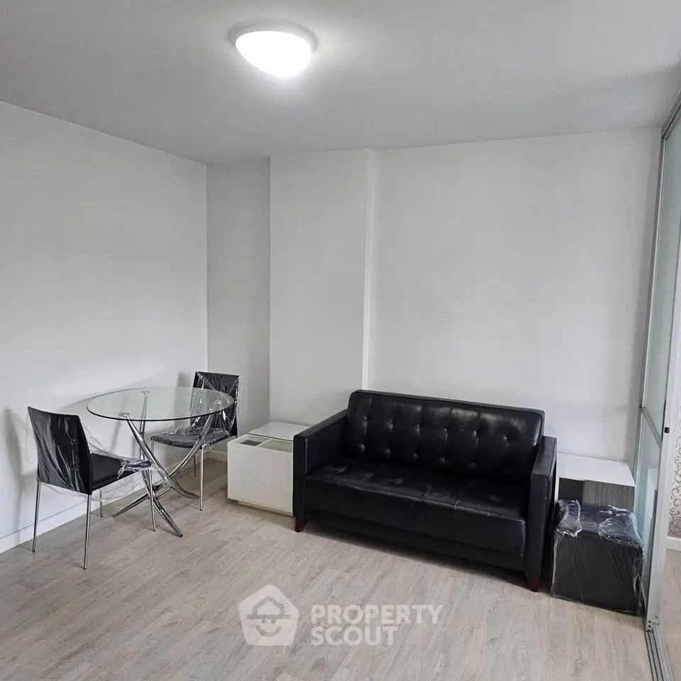 Modern living room with sleek black sofa and glass dining table, perfect for urban living.