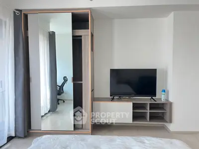 Modern bedroom with sleek wardrobe and TV unit, featuring a glimpse of a stylish study area.