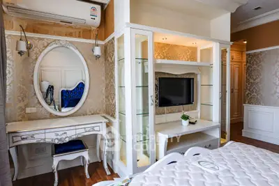 Elegant bedroom with classic decor, featuring a stylish vanity and built-in TV unit, perfect for luxury living.