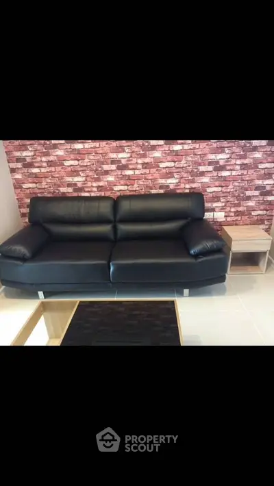 Stylish living room with black leather sofa and brick accent wall
