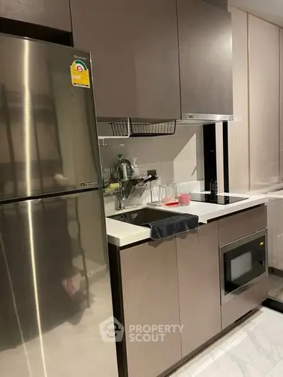 Modern kitchen with sleek cabinetry, stainless steel fridge, and built-in microwave, perfect for urban living.