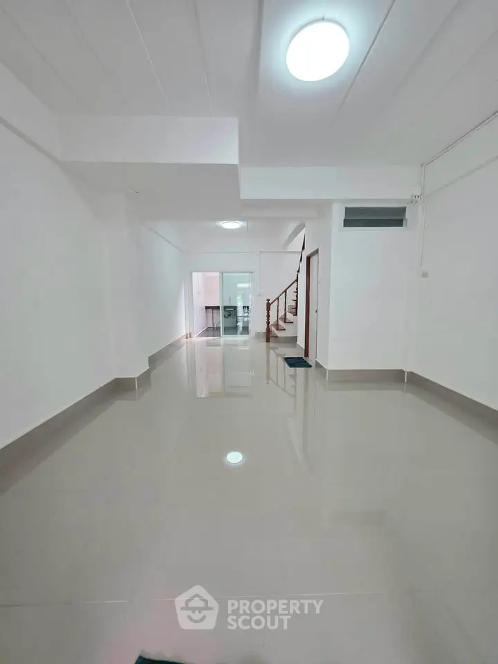 Spacious open-plan living area with glossy tiled floors and modern staircase.
