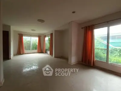 Spacious empty living room with large windows and orange curtains