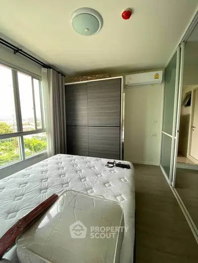 Modern bedroom with large window and built-in wardrobe in a stylish apartment.