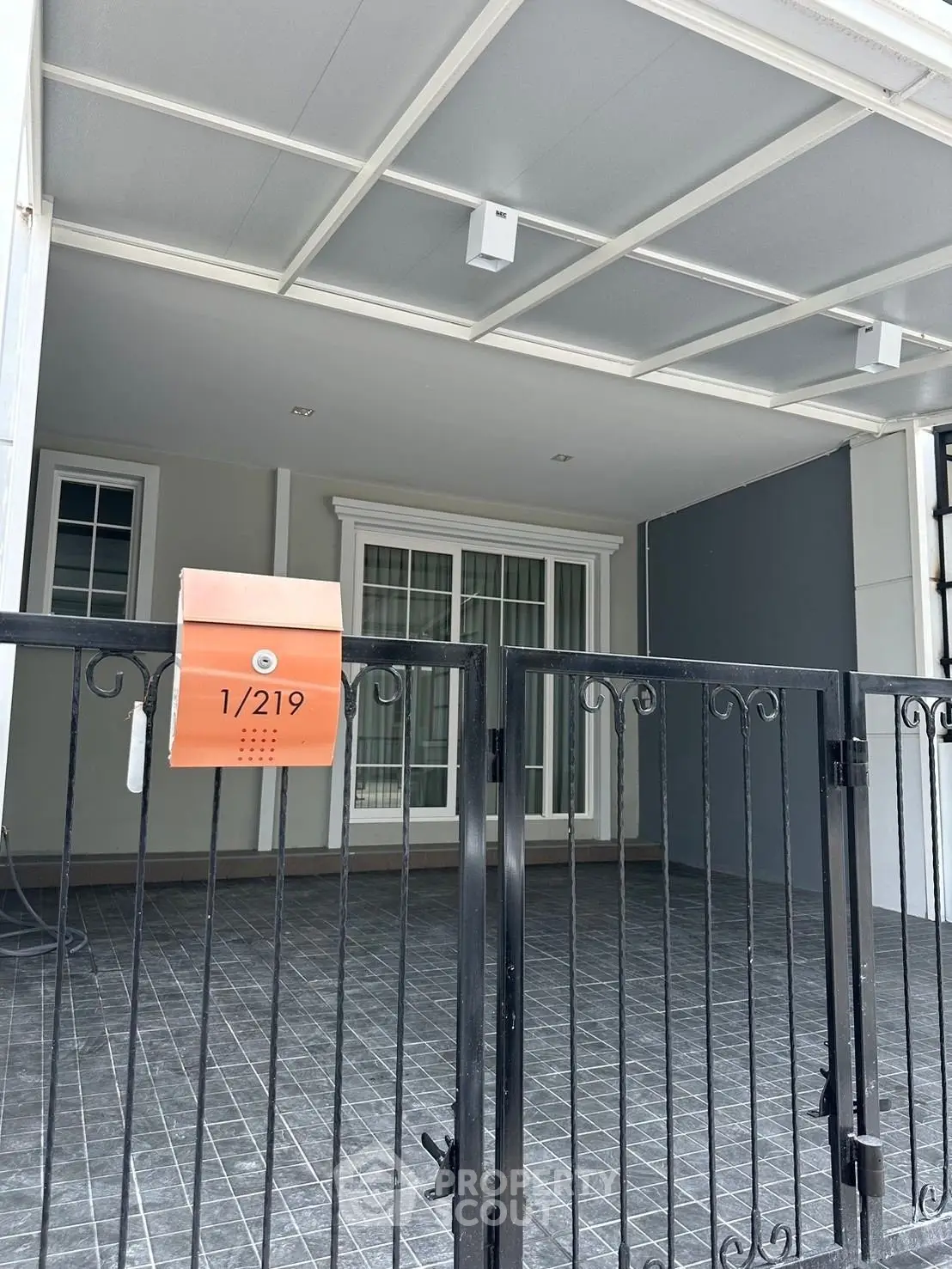 Modern townhouse entrance with gated parking area and sleek design.