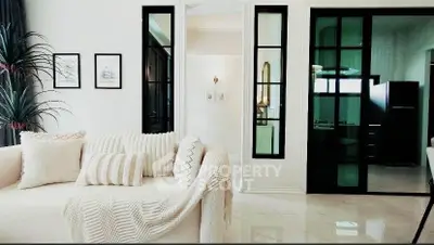 Elegant living room with modern decor and cozy seating, featuring stylish glass doors and chic wall art.