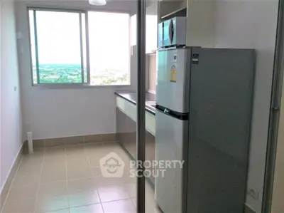 Modern kitchen with large window and sleek appliances in a high-rise apartment.