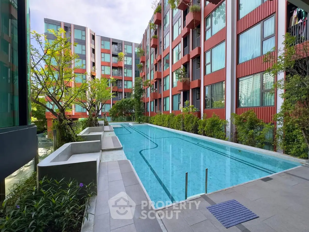 Modern apartment complex with a stunning outdoor pool and lush greenery.