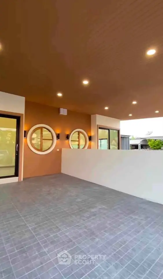 Modern covered patio with circular windows and recessed lighting, perfect for outdoor relaxation.