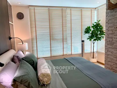 Luxurious bedroom with modern decor and large windows with blinds.