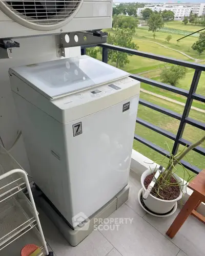 Modern washing machine on a balcony with scenic park view, ideal for urban living.