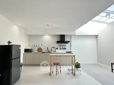 Modern kitchen with sleek design and open layout, featuring a black fridge and minimalist decor.