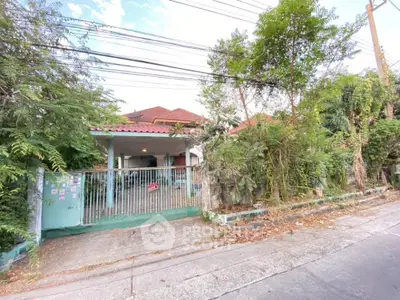 Charming single-story home with a spacious front yard, nestled among mature trees, featuring a cozy covered porch and a secure gated entrance, offering a serene suburban living experience.
