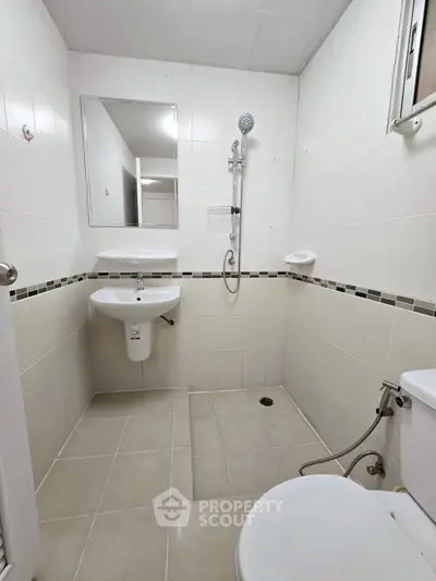 Compact bathroom with modern fixtures and neutral tiles, ideal for efficient space utilization.
