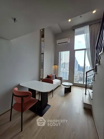 Modern duplex living room with city view, featuring stylish furniture and large windows for natural light.