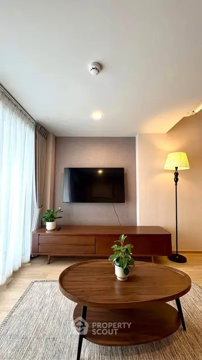 Modern living room with stylish furniture and wall-mounted TV, featuring natural light and elegant decor.