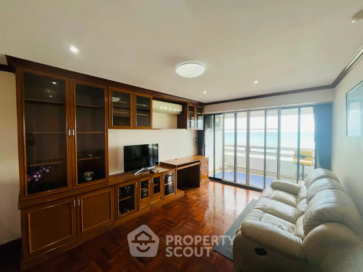 Spacious living room with elegant wooden cabinetry and stunning ocean view balcony.