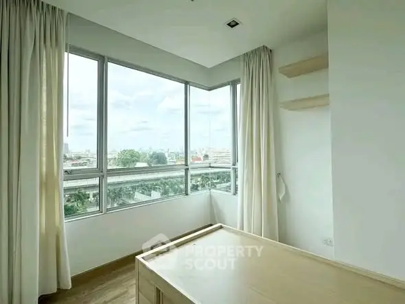Bright bedroom with large windows offering a stunning city view, perfect for urban living.