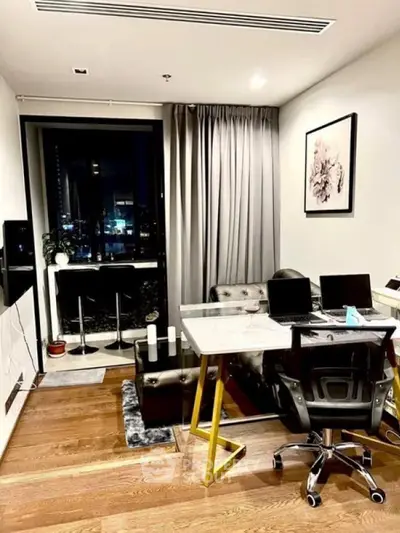 Modern living room with stylish decor and city view, featuring a sleek workspace and cozy seating area.