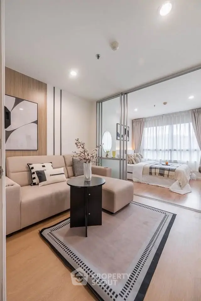 Modern living room with cozy seating and stylish decor leading to a bright bedroom with large windows.