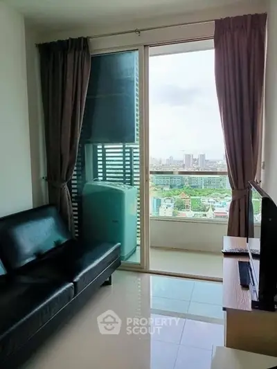 Modern living room with balcony and city view, featuring sleek black sofa and TV setup.