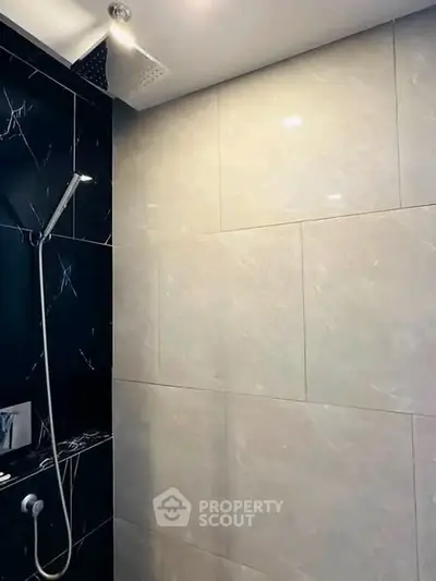 Modern bathroom with sleek black and white tiles and a rainfall showerhead.