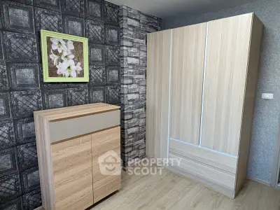 Modern bedroom with stylish wooden wardrobe and chest of drawers, featuring textured wallpaper and floral artwork.
