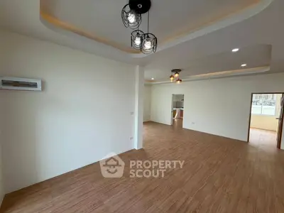 Spacious open-plan living area with modern lighting and wooden flooring