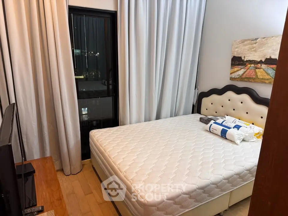 Cozy bedroom with modern decor and large window offering city views, perfect for restful nights.