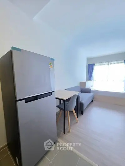 Modern studio apartment with sleek fridge and cozy living area