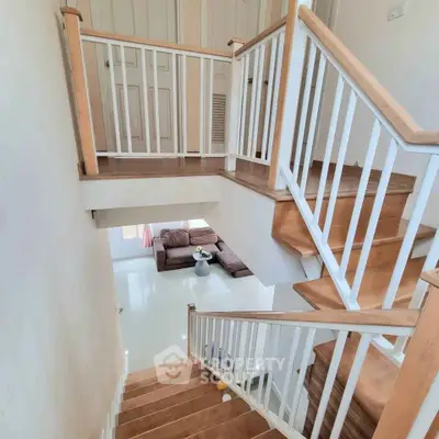 Elegant wooden staircase with modern design leading to a cozy living room.