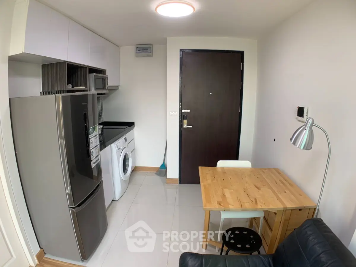 Compact modern kitchen with stainless steel appliances and cozy dining area in a stylish apartment.