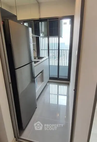 Modern kitchen with sleek appliances and balcony view in high-rise apartment.