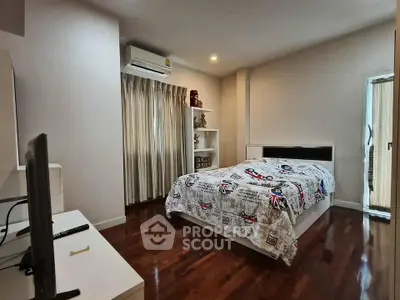 Spacious bedroom with wooden flooring and modern decor in a cozy apartment.